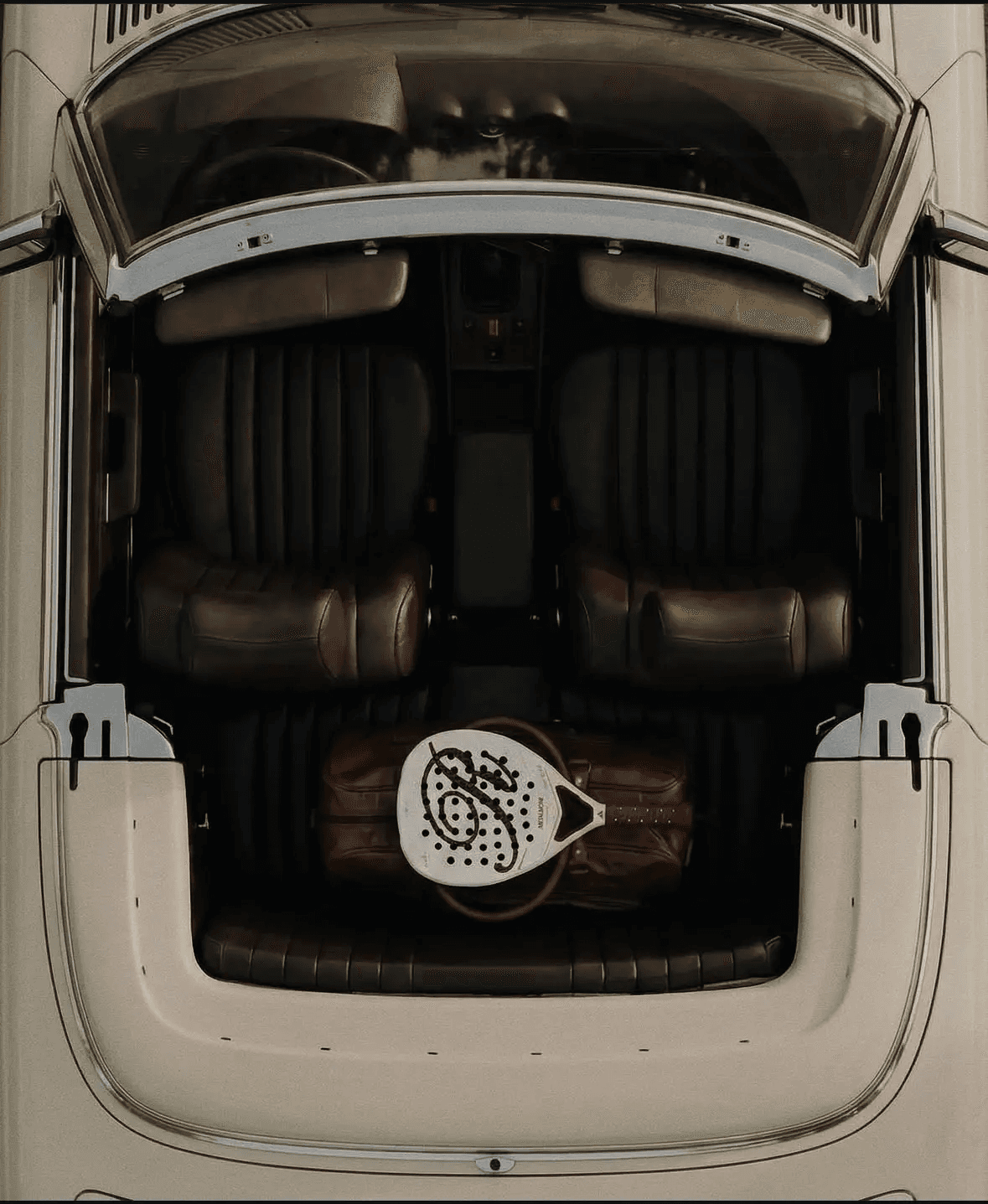 Padel racket and leather bag inside a vintage car cabin